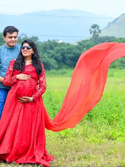 A stunning outdoor shot with a wide-open field and mountains in the distance. The red flowing gown provides a beautiful splash of color against the natural landscape.