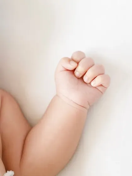 A close up on a sleeping newborn's face, showing their tiny hand curled up. Every detail is worth remembering.