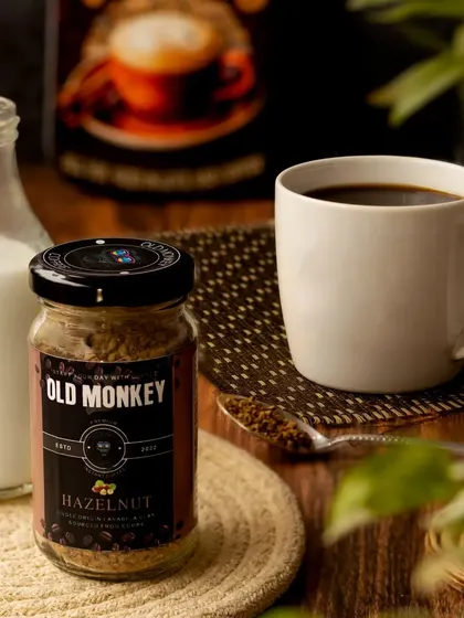 A cozy coffee moment, with a jar of hazelnut coffee, a full mug, and a small bottle of milk. The warm wooden tones and soft lighting create a comfortable and inviting atmosphere.