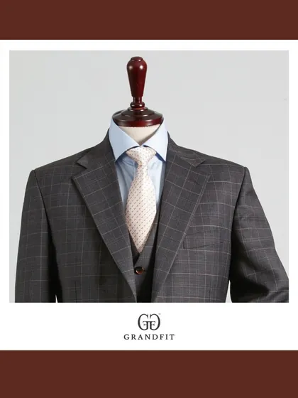A closer look at the grey plaid three-piece, emphasizing the perfect harmony between the suit fabric, the light blue shirt, and the cream-colored tie.