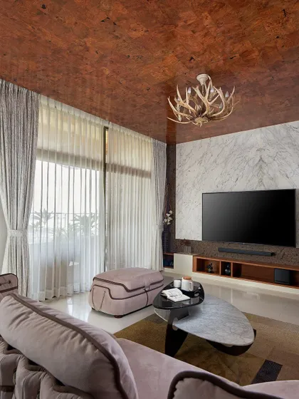 Another angle of the Sobha Indraprastha living room, showing the plush, contemporary furniture and soft drapery that balance the strong material palette. The design ensures comfort is not sacrificed for luxury.