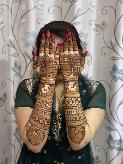 A playful shot of a bride with her beautiful mehndi, which features her initials and intricate patterns.