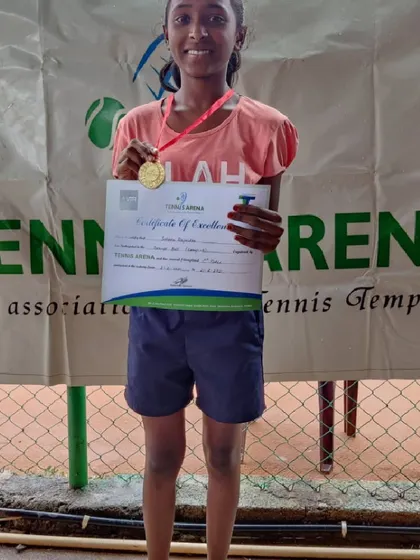 Celebrating a great performance at the Tennis Arena. This young competitor shows off her well-earned medal and certificate.
