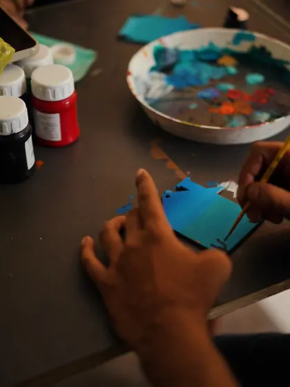 A close-up of hands at work, painting a small wooden cutout. It's all about the details.
