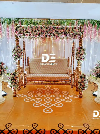 A beautiful baby shower setup featuring a floral-decorated swing and a floor covered with a traditional kolam or rangoli pattern, creating a perfect blend of elegance and tradition.