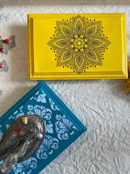 A close-up of the detailed stenciling on the yellow and teal pooja chowkis.