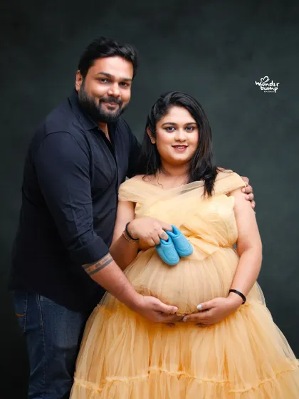 A classic couple's pose, holding tiny shoes over the baby bump. This is a popular and heartwarming shot that symbolizes the new life you are waiting for.