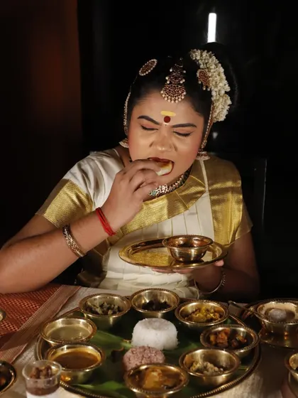 A dancer in traditional attire enjoying the Onam Sadya. This image beautifully connects the culinary and cultural aspects of the festival, showing that the feast is a core part of the celebration.