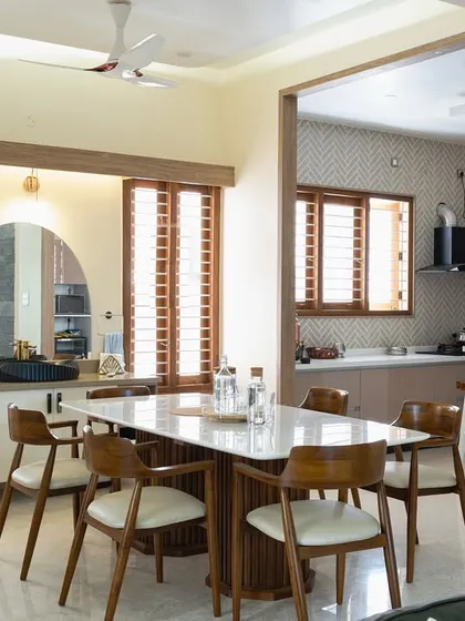A beautifully appointed dining area adjacent to the kitchen. The wooden dining table, contemporary chairs, and an arched mirror create an elegant space for family meals.