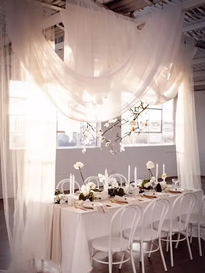 I use sheer, flowing drapes to create a private and ethereal dining space. This all-white setup is perfect for a sophisticated reception or an intimate celebration, where the focus is on elegance and light.