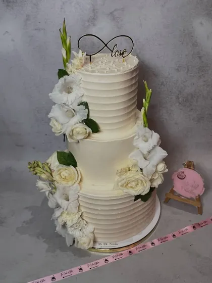 This is a classic two-tiered wedding cake I made, decorated with fresh white flowers and delicate buttercream piping. It’s designed to be an elegant and timeless centerpiece for a special day.