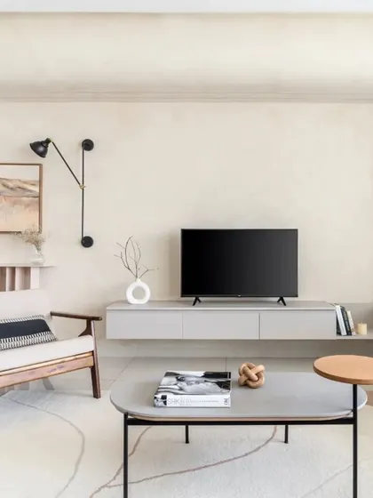 This living room from the SNN Raj Etternia project is a hideaway of grey, black, and cozy textures. A floating TV unit keeps the space feeling airy, while a statement accent chair and abstract art add personality.