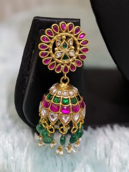 A close-up of a beautiful Jadau jhumka, with multi-colored stones and pearl drops.