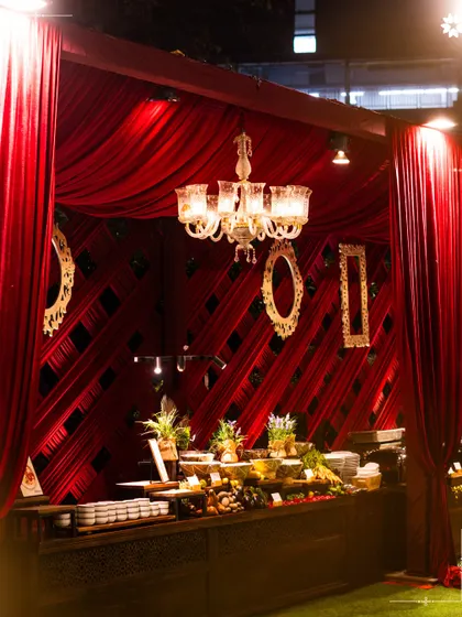 A dramatic red draped buffet station at an event in New Delhi. We design our setups to match the theme and decor of the event, creating a fully immersive experience.