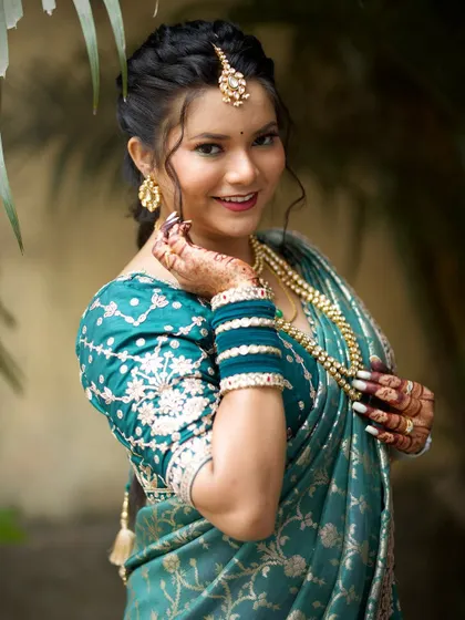 A happy, smiling bride showing off her complete look, from her jewelry to her henna.