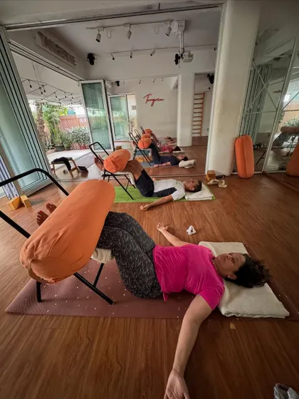 The sweet stillness after a practice. Students rest in a supported leg-up-the-chair pose, a gentle inversion that promotes relaxation and circulation.