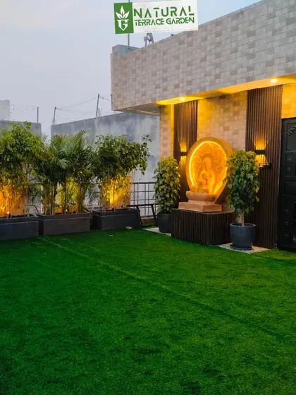 A view of the completed Uttam Nagar terrace, featuring a backlit Buddha statue and uplit bamboo plants creating a serene ambiance.
