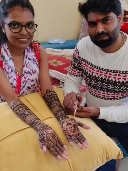 Me with a happy client, showing her freshly completed bridal mehandi featuring intricate portraits.