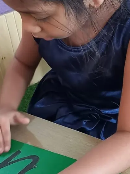 A close-up of a child tracing sandpaper letters. This multisensory approach, combining touch, sight, and sound, is a powerful way to help children learn the alphabet.