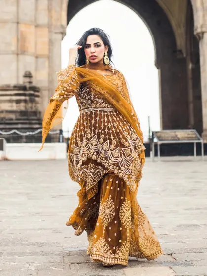 A full-length shot showcasing her stunning traditional outfit against the architecture of the Gateway. This is a great example of a fashion-forward portrait.