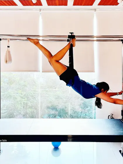 Your physical health is the canvas for your mind. This client demonstrates incredible strength and flexibility in this hanging pose on the Cadillac.