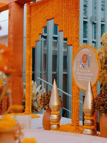 A grand entrance for a Myrah ceremony, featuring a beautiful arch made of marigold strings and a personalized welcome sign.