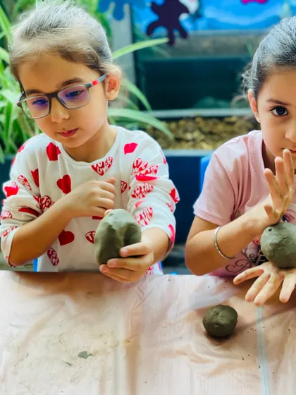 Showing off their progress! The girls hold up their clay creations during our Ganesha art workshop. We encourage kids to explore the material and make their art truly their own.