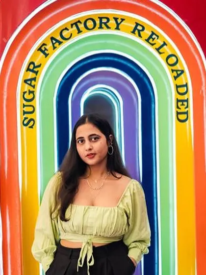 A guest posing at the colorful, illuminated entrance of Sugar Factory.