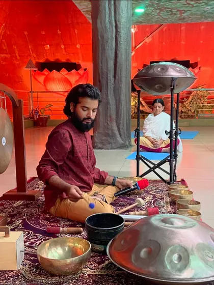 Here I am set up with my instruments, including gongs, singing bowls, and a handpan, ready to begin a sound healing journey for the group. The red lighting creates a warm, womb-like environment.