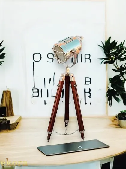 This small wooden tripod lamp is inspired by vintage nautical spotlights. The polished metal lamp head and classic brown wooden legs make it an ideal decorative lamp for a study or office desk.