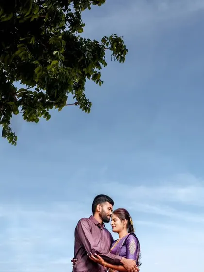 A wide shot using the sky and a tree to frame the couple, creating a sense of space and tranquility.