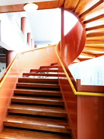 Another angle of the Sona Vistaas staircase, highlighting its smooth, continuous spiral. The design complements the earthy palette of the architecture, turning a functional element into a piece of structural art.