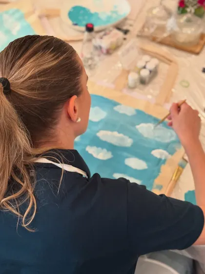 A participant paints clouds onto her canvas at The White Box event. It's all about enjoying the process.