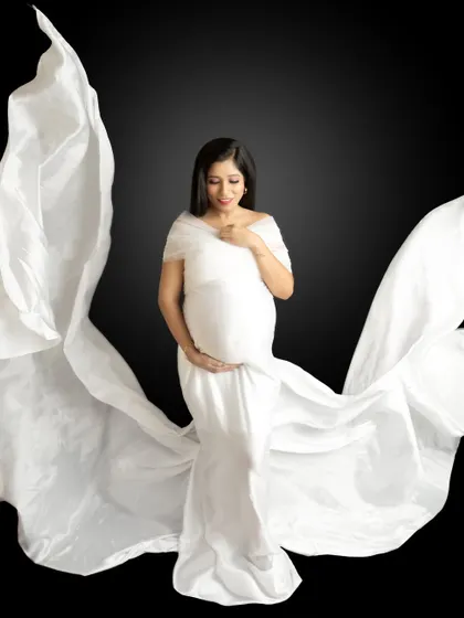 A stunning fine-art portrait with a white drape tossed to create elegant, flowing wings against a dark background.