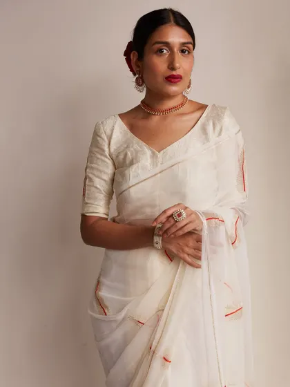 A classic, poised portrait showcasing the full look. The clean background and simple pose allow the beauty of the saree and the styling to take center stage.