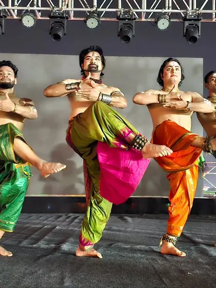 The male dancers of the 'Maheswara' production in a synchronized Chhau pose. Their powerful stance is characteristic of the martial dance form.