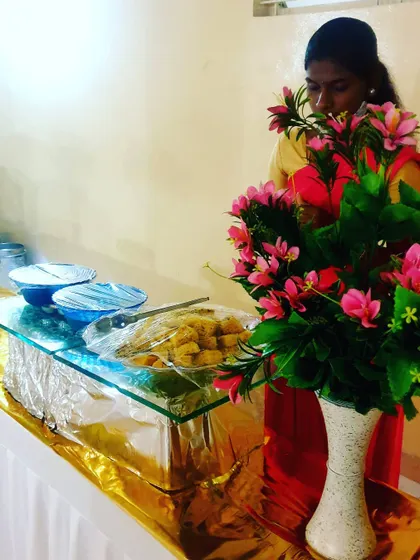 A staff member making final arrangements at a dessert and snack counter. Even simple setups are given full attention to detail.