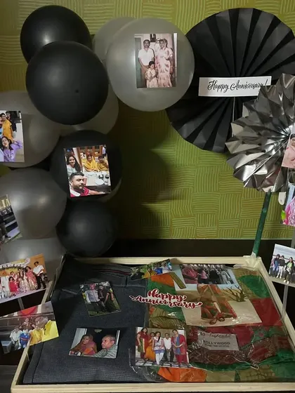 A DIY-style anniversary hamper where the focus is on memories. The tray is filled with personal photos attached to balloons and decorative fans, creating a beautiful collage of the couple's life together.