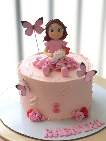 A sweet cake celebrating a little girl becoming a big sister, with a doll holding a new baby.