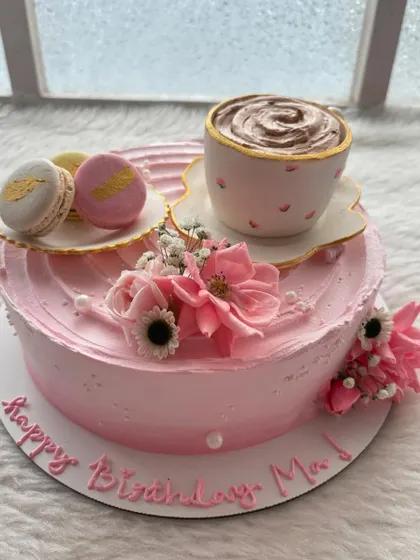 An English tea party in cake form! This pink cake features an entirely edible teacup and saucer, macarons, and delicate flowers.
