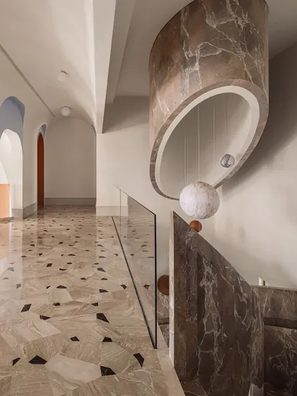 The staircase and galleria, showing the massive marble-clad light fixture that hangs from the ceiling, echoing the curve of the stairwell.