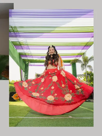 A vibrant, joyful shot of the bride twirling in her colourful lehenga during an outdoor pre-wedding event.