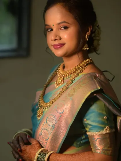 A soft and dreamy portrait of a bride. The makeup is kept minimal and glowing to highlight her natural beauty, paired with traditional gold jewelry.