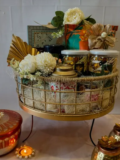 Here is our metal and jute tray hamper on a stand, making it a true centerpiece. It's overflowing with a variety of jars and boxes, promising a delightful experience for the recipient.
