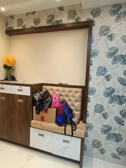 An entryway featuring a monstera leaf wallpaper next to a shoe cabinet. It's a stylish way to add personality to a functional space.