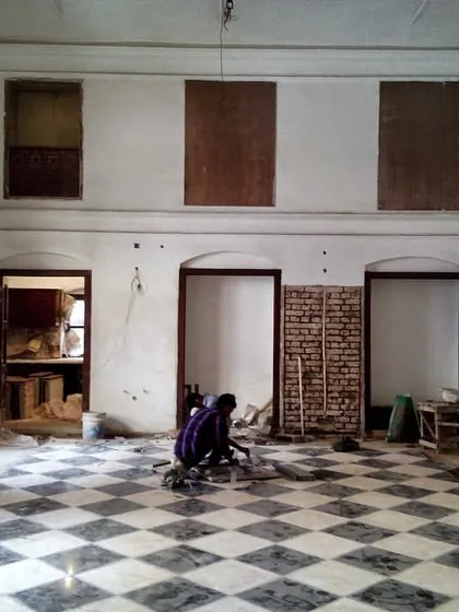 The haveli hall mid-restoration, with craftsmen meticulously laying the restored floor tiles. This phase shows the labor-intensive process of bringing a historic interior back to life, piece by piece.