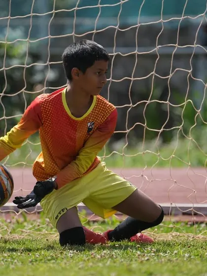 A goalkeeper demonstrates proper technique while collecting the ball during a match.