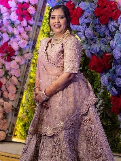 A full-length shot against a floral backdrop. The soft pink lehenga and my makeup service make for a stunning combination.