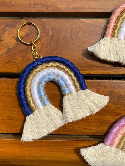 A macrame rainbow keychain in a cool blue and gold palette. This shows another color variation, perfect for matching with different styles or as a personalized gift.