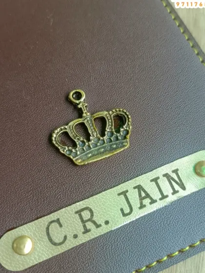 A close-up view of the customization on the passport cover. You can see the detail in the metal crown charm and the neatly engraved nameplate.